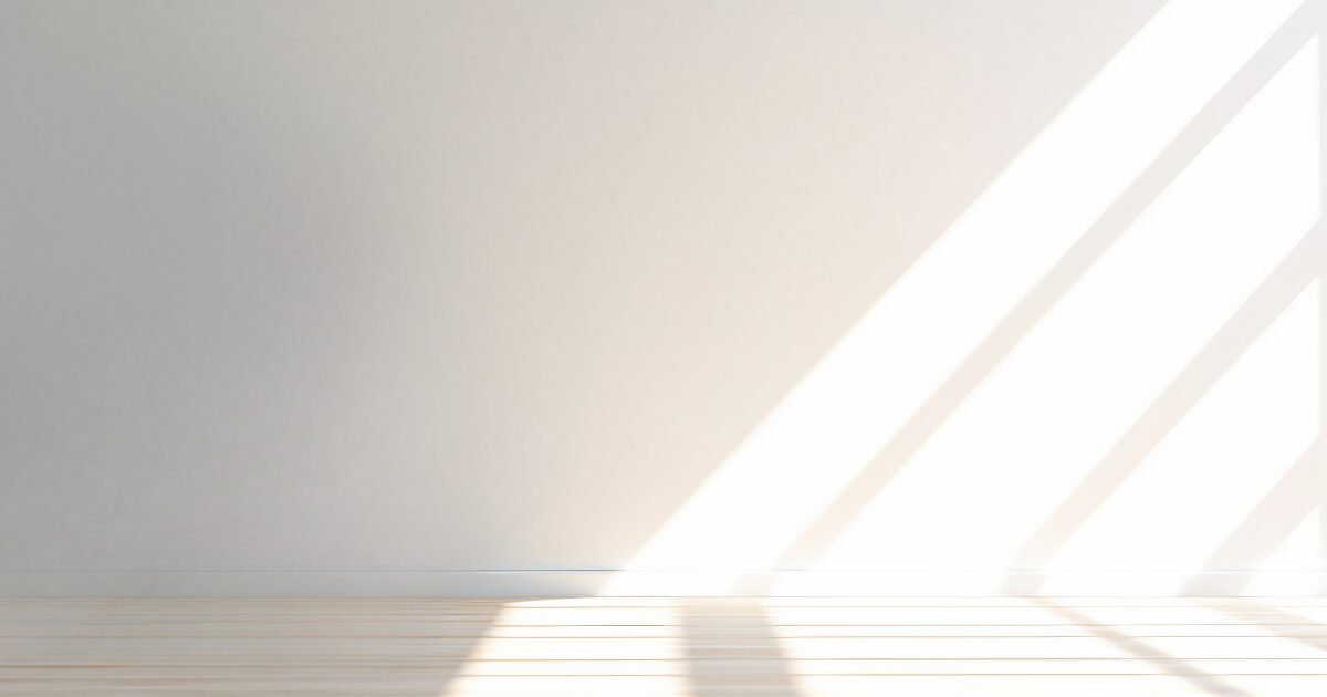 白い壁に差し込む光と影の写真